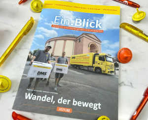 Unternehmenszeitschrift „Ein.Blick“ (2025/02) liegt auf dem Tisch umgeben von gelben und orangen Stiften