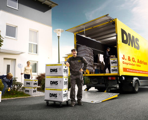 Umzugsprofi von J. & G. Adrian mit Umzugskisten vor Adrian-LKW und Wohnhaus