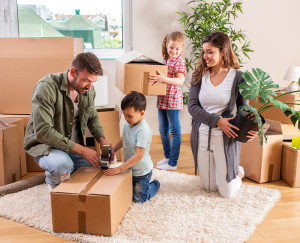 Eine Familie, Eltern mit ihren beiden Kindern, packt zusammen Umzugskartons 