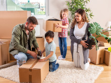 Eine Familie, Eltern mit ihren beiden Kindern, packt zusammen Umzugskartons 